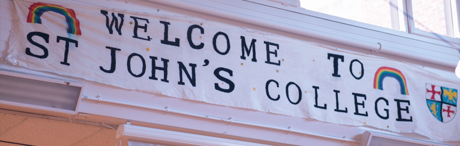 a hand painted banner with rainbows says welcome to St John's