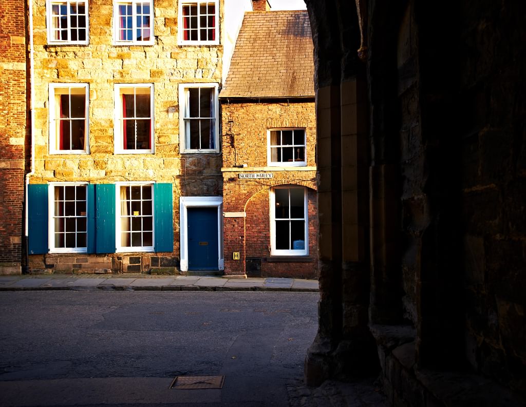 A sunlit stone house with blue shutters