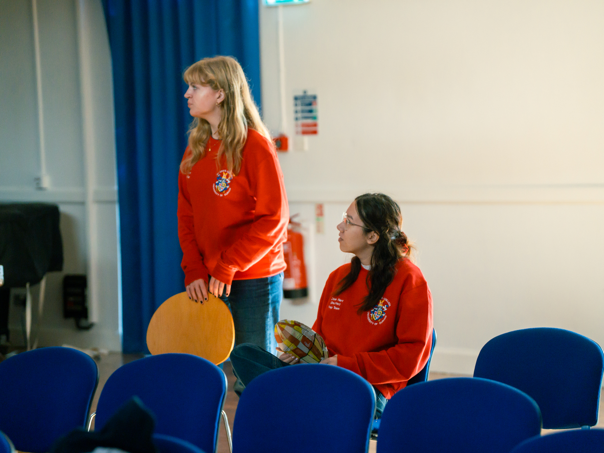 two young women in red jumpers look away from the camera